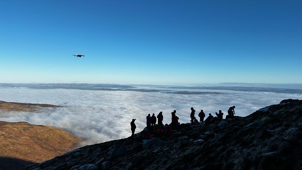 Mountain rescue team on summit above cloud inversion