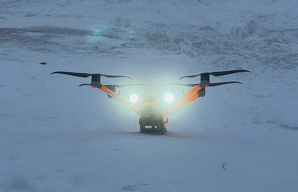 Drone with spotlights operating in snowy winter conditions